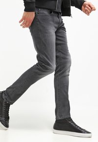 Grå denimjeans med smal passform, med framfickor och subtil sömnad. Matchas med svarta högskor.