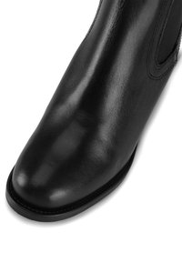 Czarne skórzane botki za kostkę o gładkim wykończeniu, z okrągłym noskiem i elastycznymi bocznymi panelami. Szycie wzdłuż krawędzi podeszwy.