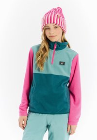 Fleece pullover in teal, roze en lichtblauw met een halve rits kraag. Draagt een lichte groene broek. Heeft een logo patch op de borst.