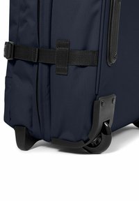 Námořnický látkový kufr s černými akcenty, bočním zipem, zesílenými rohy a dvěma hladkými kolečky pro snadnou přepravu.