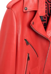 Rode leren motorjacks met zilveren hardware, ritszakken en een gestructureerde afwerking. Kenmerkt zich door een gekarteld kraag en gedurfde ontwerpdetails.