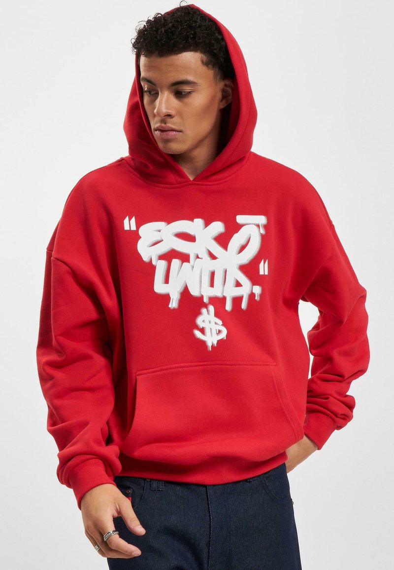 Felpa rossa con un grande logo bianco in stile graffiti sul davanti. Presenta una tasca a marsupio e un cappuccio con cordino. Tessuto morbido, vestibilità rilassata.