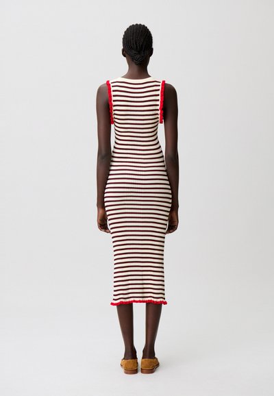 Vestito a maglia con righe verticali rosse e bianche, design aderente, trama a coste, dettagli a volant rossi sulle bretelle e orlo al ginocchio.