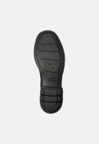 Svart gummisula med texturerat grepp, med upphöjda mönster och varumärket "CAMPER" präglat. Robust och designad för bra fäste.