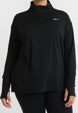 Person iført en sort langærmet træningstrøje med kvartlynlås og tommelfingerhuller, med en lille Nike-logo på brystet.