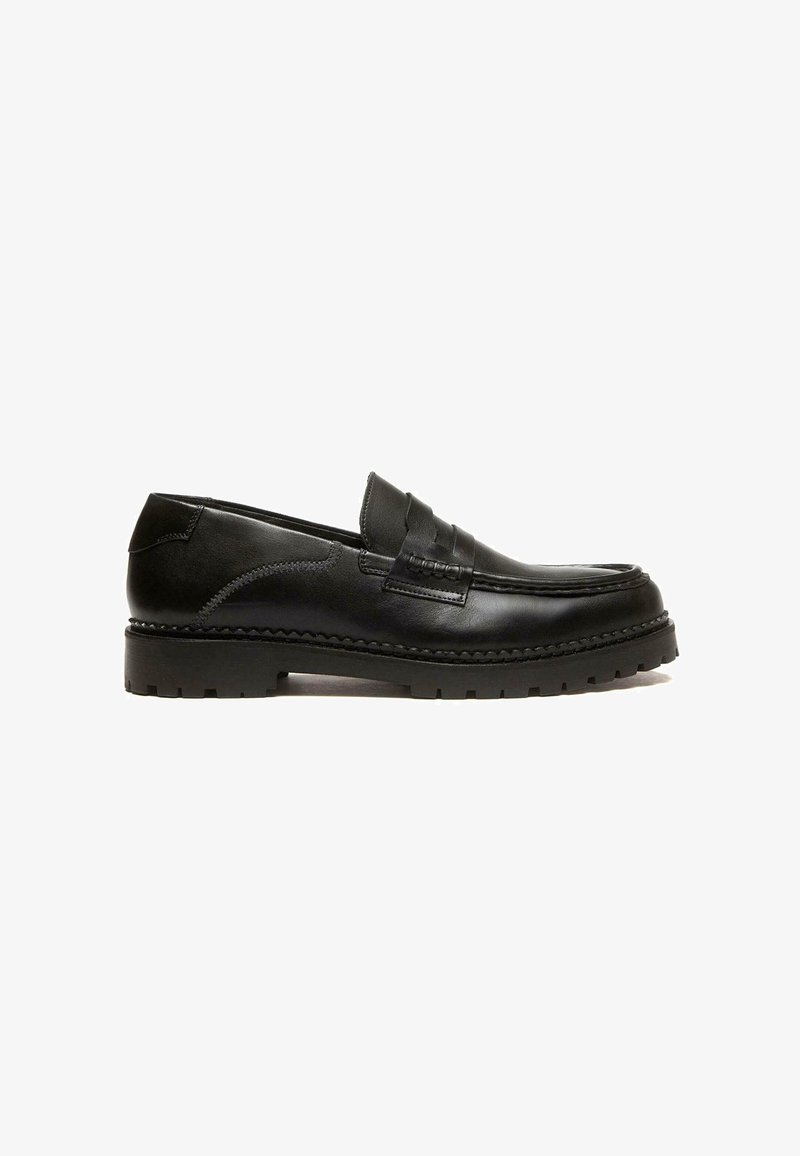 Mocassino in pelle nera con design cucito, profilo basso e suola in gomma texturizzata. Presenta una fascia ampia nella parte anteriore e una finitura liscia.