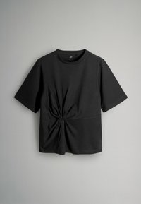 Melnā T-kreklā, kas izgatavots no mīksta auduma, ir īsas piedurknes un mezgla detaļa jostasvietā, ar apaļu kakla izgriezumu un gludu tekstūru.