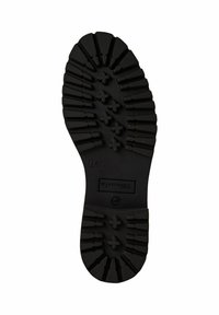 Semelle en caoutchouc noir avec des motifs de tread profonds et angulaires, présentant des marques croisées surélevées pour une adhérence et une zone d'arche lisse.
