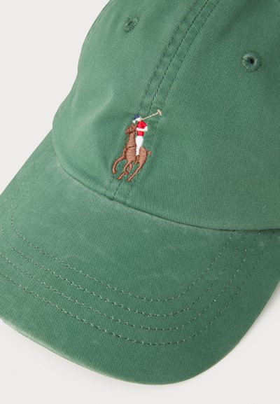 Zielona bawełniana czapka z zakrzywionym daszkiem i haftowanym wzorem polo gracza w kolorach brązowym, czerwonym i niebieskim. Zawiera szczegóły szycia na daszku.