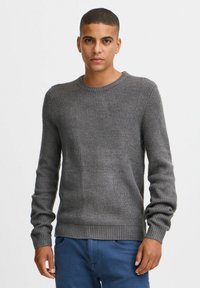 Pulover gri din tricot cu model, cu mâneci lungi �și guler rotund. Prezintă o suprafață texturată și un brâu ajustat.