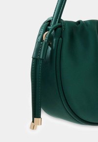 Zielona satynowa torebka w zaokrąglonym kształcie, z zebranym wierzchem, szczegółami z węzłem i złotymi akcentami. Gładka tekstura i prosty design.
