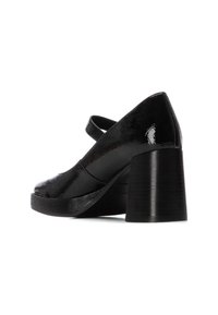 Zapato de charol negro con punta redondeada, una sola correa y tacón grueso. Textura suave con un acabado brillante.