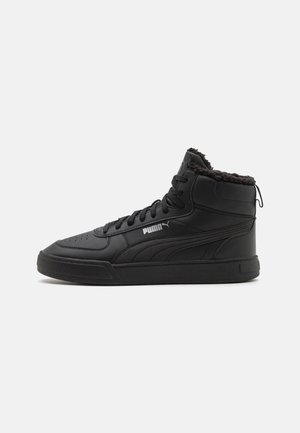 Baskets montantes noires Puma avec lacets à l'avant, doublure en fausse fourrure et logo Puma sur le côté, présentées de profil sur fond blanc.