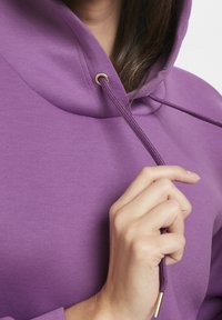 Sweat à capuche violet avec cordon de serrage orné d'accents dorés, présentant une texture lisse et une coupe décontractée autour de l'encolure.