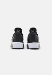 Un paio di sneakers Nike Air Max nere e bianche viste da dietro su uno sfondo bianco semplice.