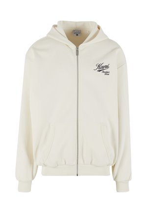 Krémová mikina na zips s kapucňou, prednými vreckami, rebrovanými manžetami a čiernym logo v písme na ľavej strane hrude. Mäkká, textúrovaná tkanina.