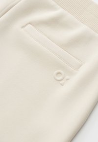 Beige Jogginghose aus weichem Stoff, mit einem gerippten Bund, einer einzelnen Gesäßtasche und einem tonalen, geprägten Logodetail.