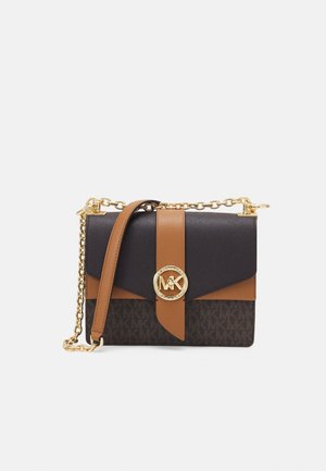 Sac bandoulière noir et marron avec bandoulière chaîne dorée et fermoir rond avec logo MK sur le rabat avant.