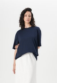 T-shirt oversize blu navy realizzato in tessuto morbido, con scollatura rotonda e maniche corte, abbinato a una gonna bianca a texture.