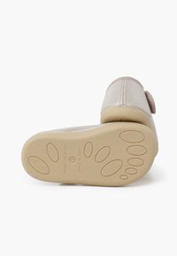 Zapato de cuero plateado con una suela de goma texturizada en color beige. Presenta una puntera redonda y un lazo decorativo. Fabricado en España, talla 21.