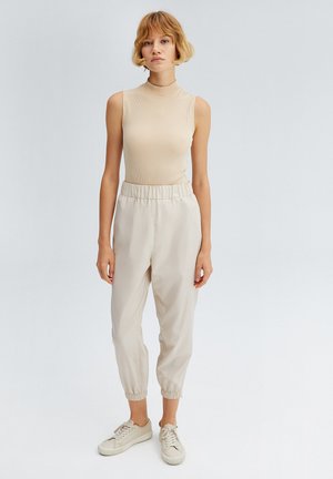 Beige ribbet senza ærmer, elastisk talje beige joggers og lyse sneakers. Simpelt design med en glat tekstur og en afslappet pasform.