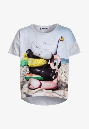 T-Shirt mit kurzen Ärmeln, das eine Grafik von gestapelten aufblasbaren Poolspielzeugen zeigt, darunter einen Schwan, einen Flamingo und eine Ente, vor einem Strandhintergrund.