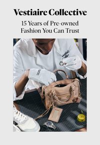 Personne portant des gants blancs inspecte une bague au-dessus d’un sac à main beige avec une montre, une chaussure et un ruban à mesurer sur la table.