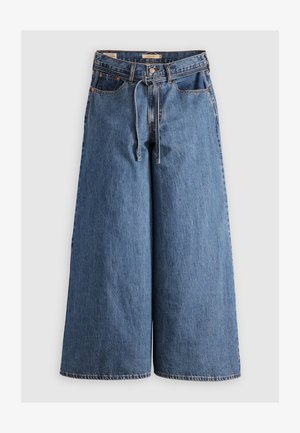 Calças de ganga de perna ampla em azul médio com uma cintura alta, apresentando um cordão, cinco bolsos e detalhes de costura em contraste.
