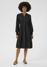 Zwarte denim jurk met lange pofmouwen, een V-hals met knopen, een relaxte pasvorm en een zoom tot op de knie. Glad textuur met een subtiele glans.