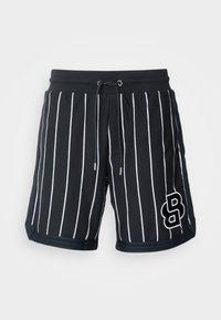 Shorts à rayures noires et blanches avec une taille à cordon, en tissu texturé, présentant un logo sur le bas côté droit.