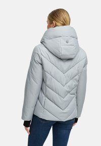 Veste matelassée gris clair avec un motif en chevrons, col montant et capuche. Présente des coutures élégantes et un logo de marque au dos.