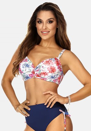 Stanik bikini w kwiatowy wzór z twistem w białym kolorze, ozdobiony kolorowymi kwiatami. W połączeniu z ciemnoniebieskimi majtkami o wysokim stanie z regulowanymi wiązaniami.