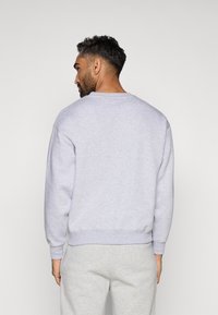 Sweatshirt cinza-claro com gola redonda e punhos canelados, feito de uma mistura de algodão suave; apresenta um corte descontraído e detalhes de costura mínimos.