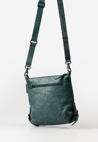 Borsa in pelle verde acqua con una texture liscia, caratterizzata da una tasca frontale con zip, cinturino regolabile e chiusure a scatto sui lati.