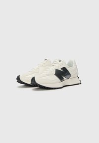 White athletic shoes with a textured suede and mesh upper, featuring a black N logo and a black rubber sole with traction pattern.