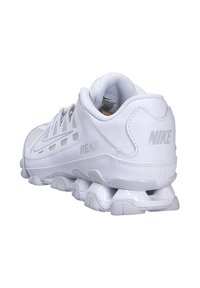 Scarpe da corsa Nike REAX bianche, con tomaia sintetica, dettagli in mesh, collo imbottito e design distintivo della suola elastica.