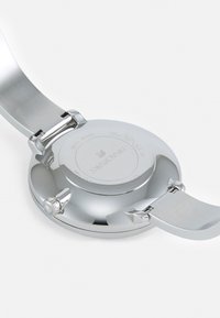 Orologio in acciaio inox argento con cassa rotonda, finitura liscia e cinturino con chiusura. Presenta una corona e un logo impresso sul retro.