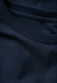 Dunkelblauses Baumwoll-T-Shirt mit einem gerippten Ausschnitt, das über eine glatte Textur verfügt und ein Etikett mit dem Markennamen "Intimissimi" sichtbar ist.