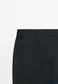 Dark linen trousers featuring a flat front with belt loops and a back pocket. The texture is smooth with a subtle sheen.
