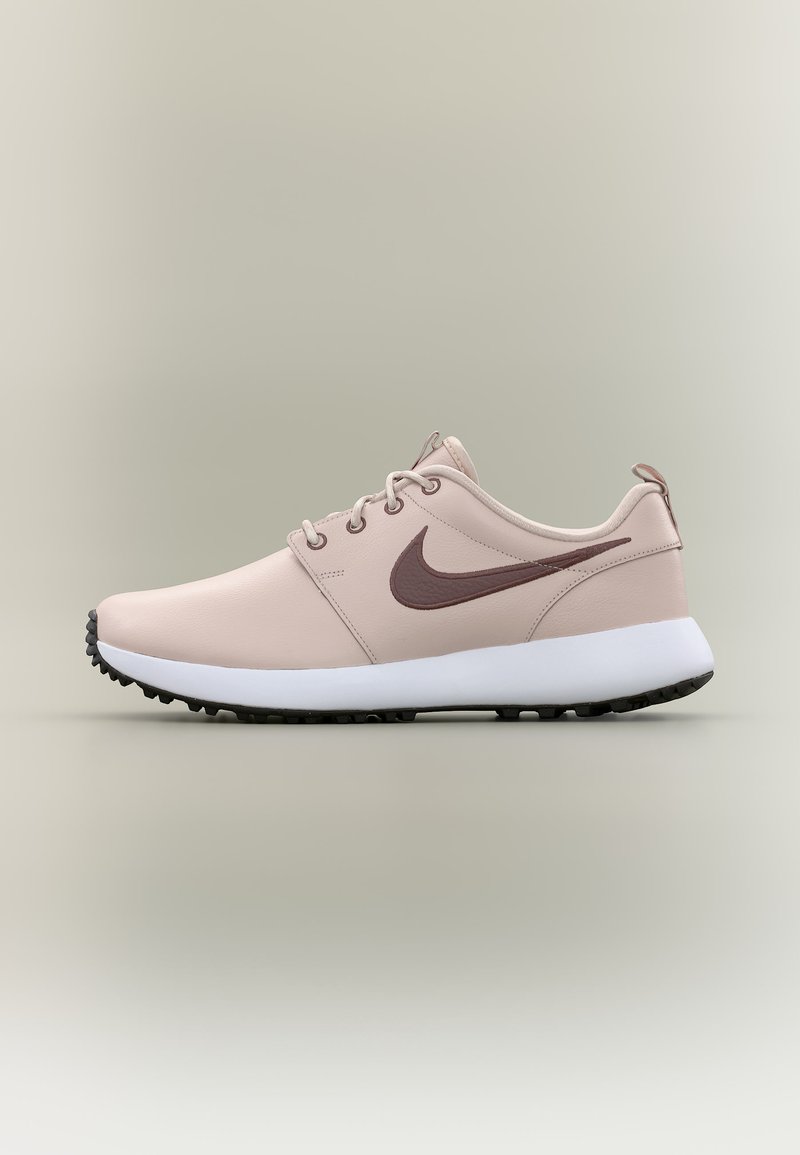 Hellrosa Nike-Sneaker mit braunem Swoosh-Logo, weißer Sohle und schwarzer Profilsohle, von der Seite vor neutralem Hintergrund gezeigt.