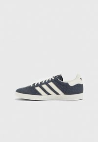 Navy denim-sneakers med vita ränder, texturerad tyg, rund tå och krämfärgad gummisula. Har klassisk snörning.