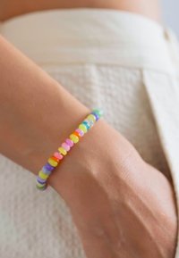 Värviline helmesõrmus, mis koosneb erinevatest pastelltoone sisaldavatest ümaratest helmestest, valmistatud läikivast plastikust, millel on sile tekstuur.