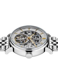 Montre squelette en argent avec un cadran argenté à motifs, des accents dorés et un bracelet en acier inoxydable. Comprend un boîtier rond et une couronne.