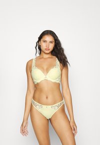 Sutiã de renda amarelo limão com bordas rendadas e aro, combinado com cuecas corresponder com detalhes em renda, ambos com padrões florais.