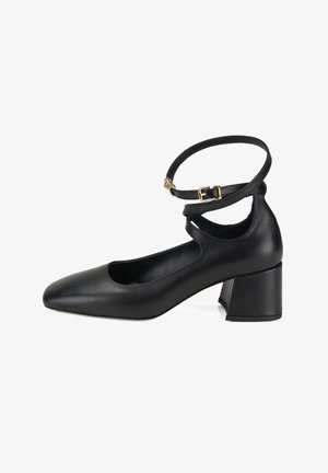 Black leather mid-heel shoe with pointed toe and double ankle straps featuring gold-tone buckles on a white background.