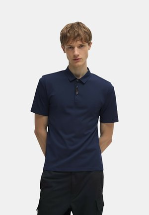 Polo shirt blu navy realizzato in tessuto liscio, con bottoni, maniche corte e un logo discreto sulla manica sinistra.