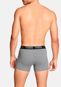 Graue Boxershorts aus weichem Stoff mit einem schwarzen elastischen Bund, der das Logo "PUMA" zeigt. Glatte Textur und enger Sitz.