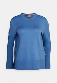 Modrý pletený svetr s kulatým výstřihem, dlouhými rukávy a rovným lemem. Má malý logo na hrudi a žebrované manžety.