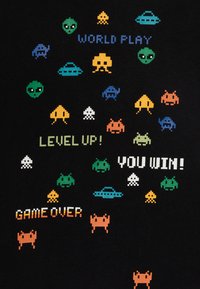Tessuto nero con disegni pixellati colorati di alieni e astronavi. Frasi testuali includono "WORLD PLAY," "LEVEL UP!," "YOU WIN!" e "GAME OVER."