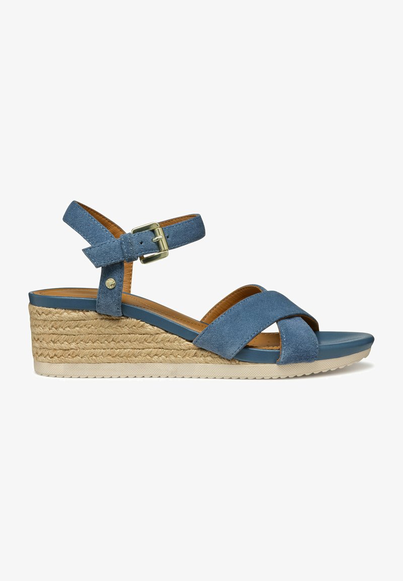 Sandale compensée bleue en suède avec des sangles croisées, boucle à la cheville, plateforme en jute et semelle en caoutchouc texturé. Elle possède une doublure intérieure lisse.
